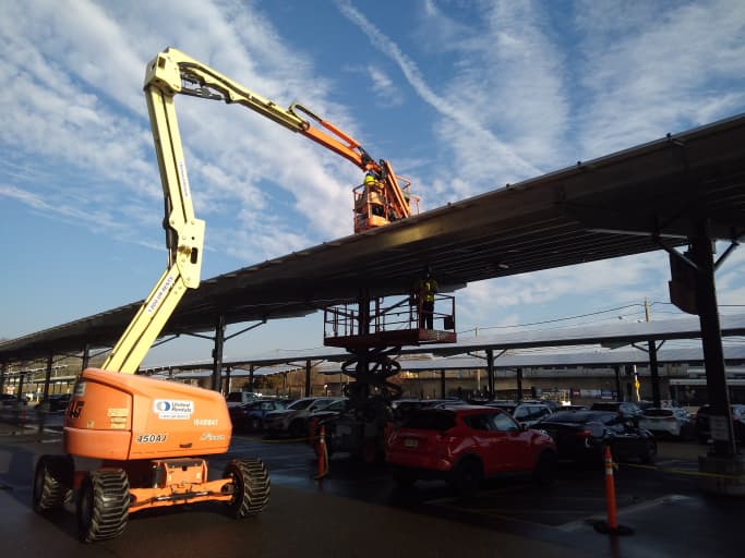 Different types of construction lifts including boom lifts, scissor lifts, and telehandlers sitting idle in an equipment yard.